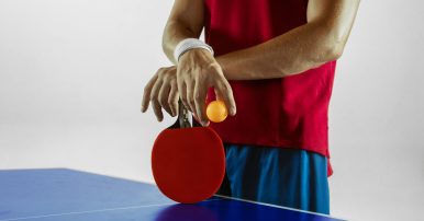 Young man plays table tennis on white studio background. Model in sportwear plays ping pong. Concept of leisure activity, sport, human emotions in gameplay, healthy lifestyle, motion, action, movement.